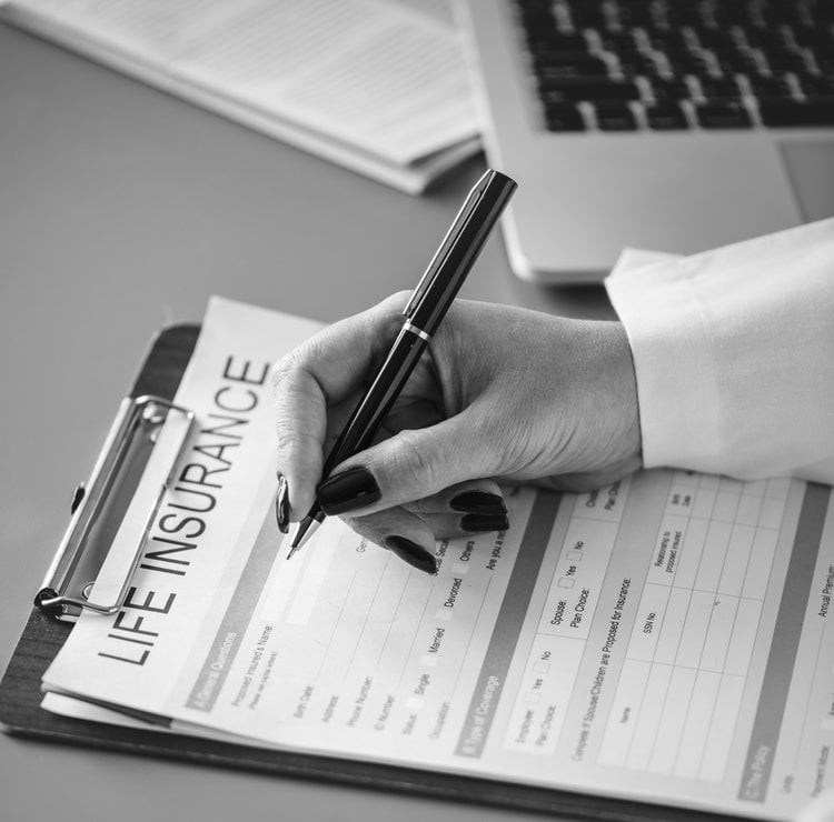 Closeup of doctor filling life insurance form